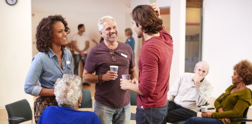 This image: photo of some adults having a friendly discussion.
					The map: the map has zoomed out to show the full site boundary, with a
					map marker in the middle, which opens the survey when clicked.